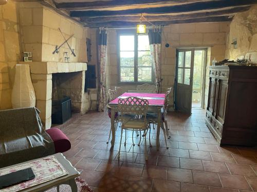 une salle à manger avec une table et une cheminée dans l'établissement L’escale Troglo au bord de la Loire, à Souzay-Champigny