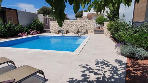 una piscina en un patio con sillas y plantas en Premium Appartments Suha Punta, en Rab