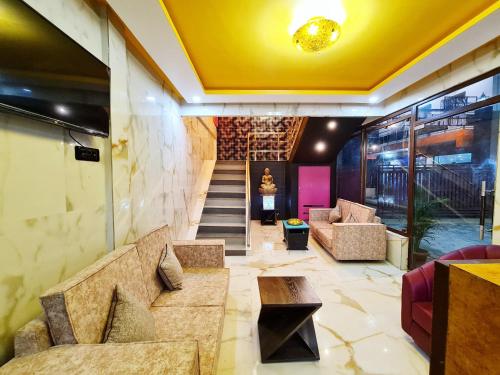 a lobby with stairs and a yellow ceiling at Hotel Aurelia Pearl in Patna
