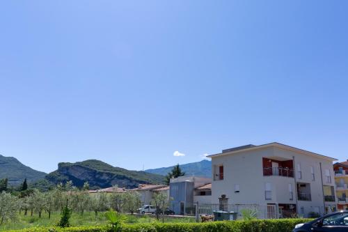 una casa blanca con montañas en el fondo en Appartamento Campagnola con giardino privato e due camere da letto, en Riva del Garda