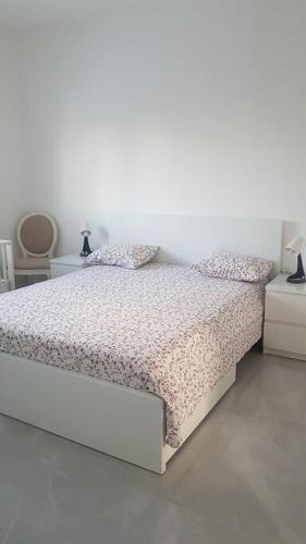 a white bedroom with a bed and two tables at Appartement cosy entre mer et ville avec parking gratuit a proximite in Netanya