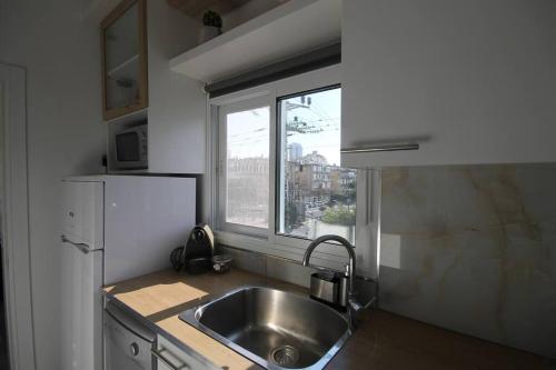 a kitchen with a stainless steel sink and a window at Appartement cosy entre mer et ville avec parking gratuit a proximite in Netanya
