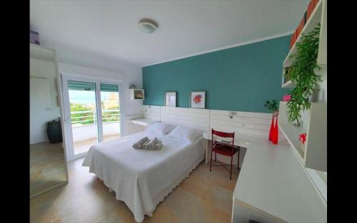 1 dormitorio con 1 cama blanca y 1 silla roja en Apartamento Cobertura PALMAS DO ARVOREDO para 7 pessoas a 250m do mar com terraço e vista maravilhosa, en Governador Celso Ramos