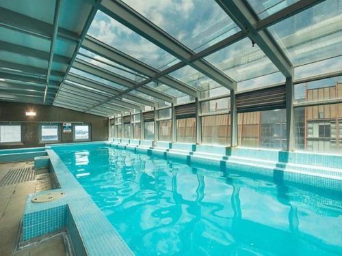 a large indoor swimming pool with a large window at La Sky Boutique Apartment - Pool, Spa & Sauna in Melbourne