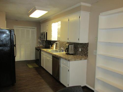a kitchen with white cabinets and a black refrigerator at Cayce Charm Minutes to Downtown Columbia in Cayce