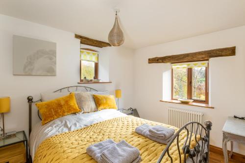 a bedroom with a bed with yellow pillows at Granary Cottage - Luxury Barn Conversion in Weston Subedge