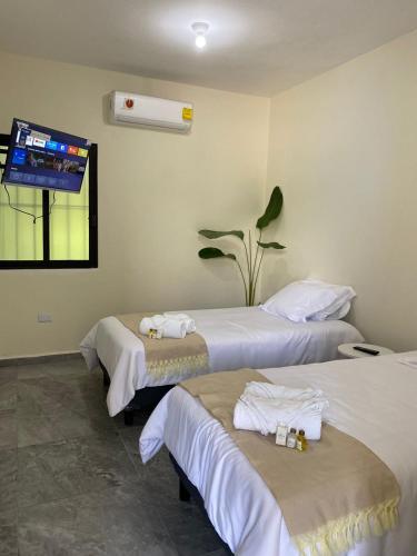 a hotel room with two beds and a flat screen tv at Hotel La Isla in Cunduacán