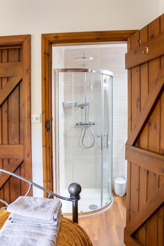 a shower with a glass door in a room at Granary Cottage Luxury Barn Conversion in Weston Subedge