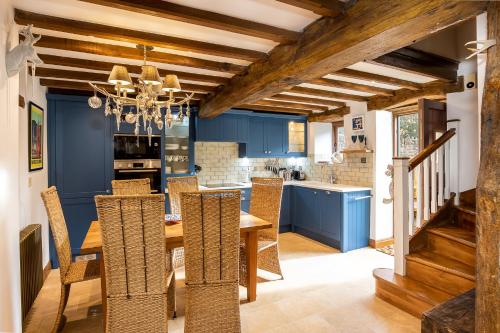 ein Esszimmer mit blauen Wänden und einem Holztisch und Stühlen in der Unterkunft Granary Cottage - Luxury Barn Conversion in Weston Subedge