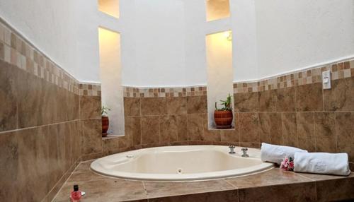 a large bathroom with a large tub with two windows at Hotel Boutique La Española in Villa de Leyva