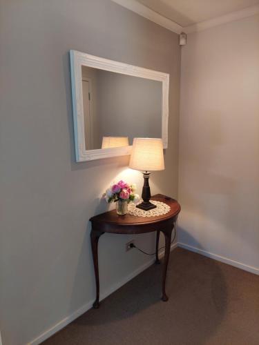 a table with a lamp and a mirror on a wall at The Grey Studio@13a in Carterton