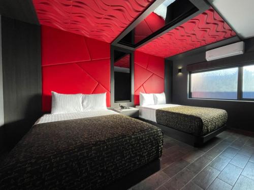 1 dormitorio con 2 camas y pared roja en HOTEL PASSION SECRETS VILLAS AND SUITES en Toluca