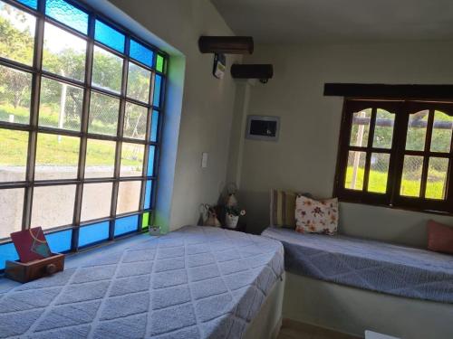 1 Schlafzimmer mit 2 Betten und großen Fenstern in der Unterkunft las brisas casas de campo un lugar para soñar in San Antonio de Arredondo