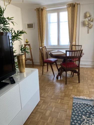 a living room with a table and chairs and a tv at TANGO appartement de charme calme lumineux 75m2 6 personnes in Mulhouse