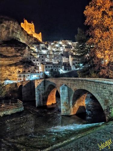 a bridge over a river with a town in the background at Casa Rural con Jacuzzi Paraíso del Júcar in Alcalá del Júcar
