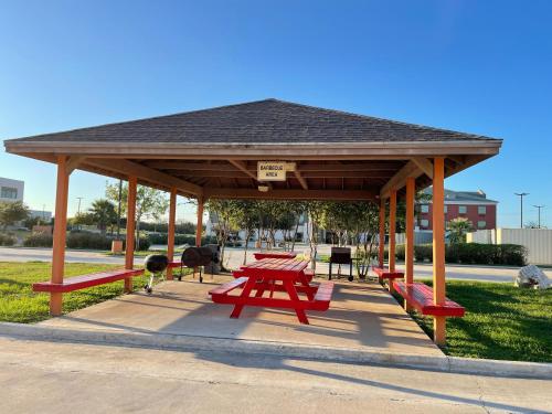 a picnic shelter with red picnic tables in a park at Sunbridge Inn & Suite Extended Stay in Jourdanton