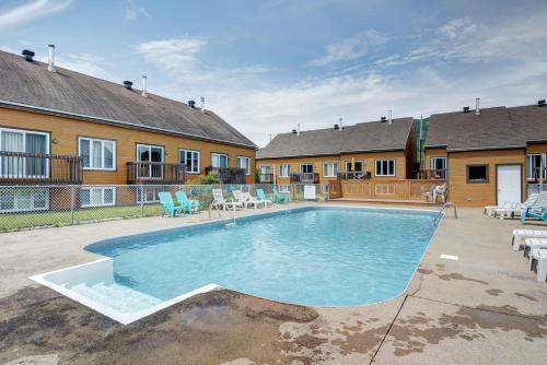 a swimming pool in a yard with chairs and a house at condo sainte-anne in Beaupré