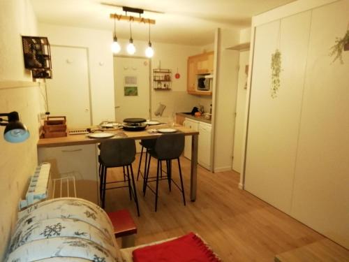 une cuisine avec une table et des chaises dans une pièce dans l'établissement La Plagne Les Coches studio divisible ensoleillé, à La Plagne Tarentaise