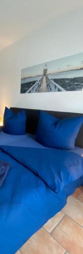 a bed with blue pillows on top of it at FeWo-Airport in Blankenfelde