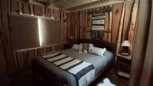 1 dormitorio pequeño con 1 cama en una habitación de madera en Cabañas Rustica Pucon Río Trancura, en Pucón