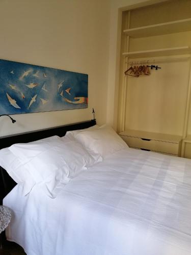 a white bed in a bedroom with a painting on the wall at Poggetto home in Florence