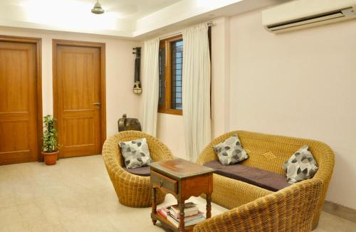 a living room with two wicker chairs and a couch at Aashianaa Gracious Living in New Delhi