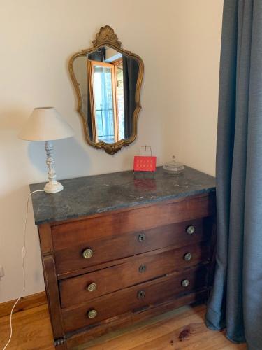 a dresser with a mirror and a lamp on it at Maison cosy cœur de bastide+ cour + vue sur toits in Eymet