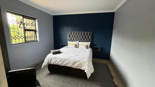 a bedroom with a bed with blue walls and a window at MySA in Durban