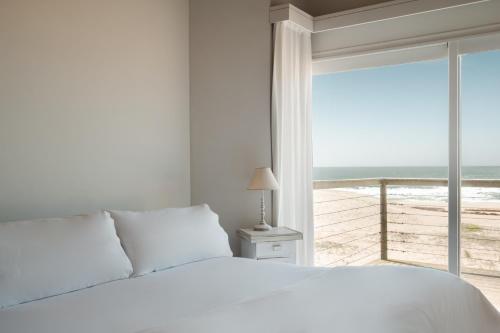 a bedroom with a bed and a view of the ocean at MarAdentro Apart Hotel & Suites in Punta Del Diablo