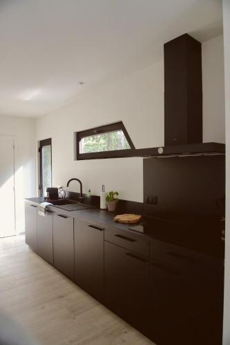 a kitchen with black cabinets and a sink at Sweet Valley Madeleine in Zutendaal