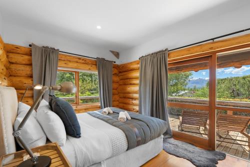 a bedroom with a bed and a large window at The Log House in Wanaka