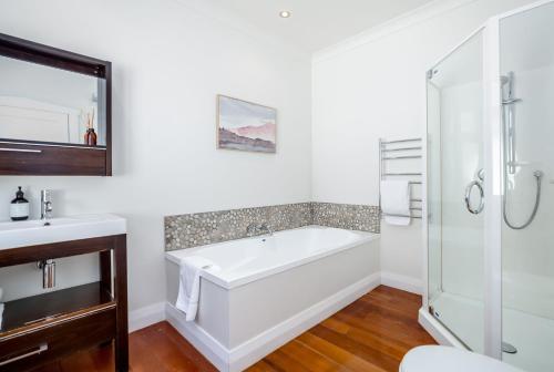 un baño con bañera y ducha de cristal en Brooklands Cottage The Award Winning Villa, en Martinborough