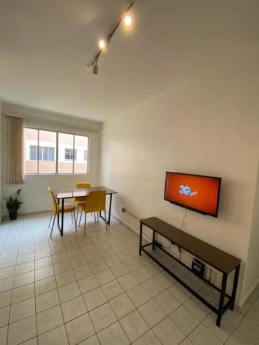 uma sala de estar com uma mesa e uma televisão na parede em Vale Hospedar Paulo Coelho Apart em Petrolina