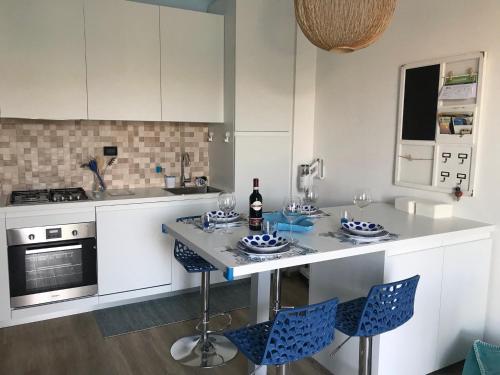 eine Küche mit weißen Schränken und einem Tisch mit blauen Stühlen in der Unterkunft my happy place in Lido di Camaiore