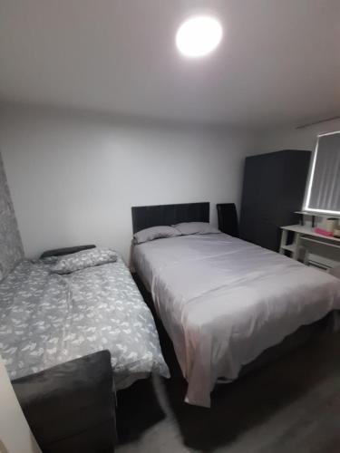 a bedroom with two beds and a light on the wall at Glorious BnB Longbridge in Longbridge