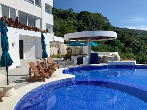 uma piscina com cadeiras e guarda-sóis ao lado de um edifício em La Villa de Almudena em Acapulco