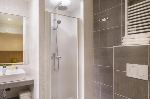 W łazience znajduje się prysznic i umywalka. w obiekcie Hotel Bel Oranger Gare de Lyon w Paryżu