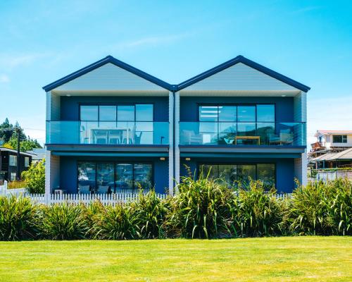a large blue house with a lawn in front of it at Boathouse Apartments in Picton