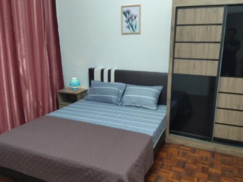 ein Schlafzimmer mit einem Bett mit blauen Kissen in der Unterkunft Pinang Beach Cottage @ Ferringhi in Batu Feringgi