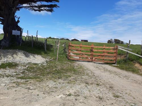 a wooden fence on a dirt road next to a field at Cabañas MAR BRAVA in Ancud