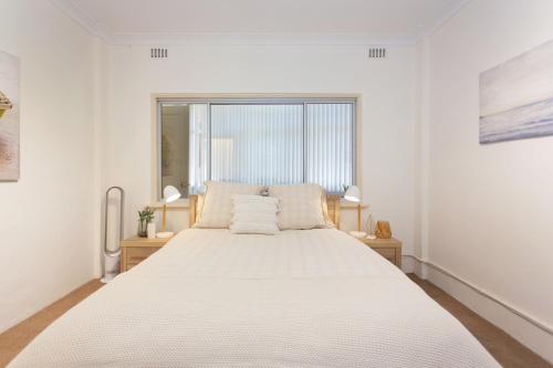 柏斯的住宿－Arcadia Apartment - Cottesloe，卧室配有一张大白色床和窗户