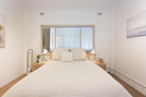 a bedroom with a large white bed with a window at Arcadia Apartment - Cottesloe in Perth
