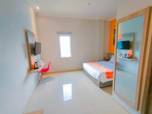 a bedroom with a bed and a chair and a mirror at Front One Budget Waena Abepura in Abepura