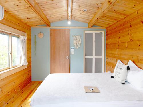 宮古島にあるゲストハウス コアの木製の部屋に白いベッドが備わるベッドルーム1室