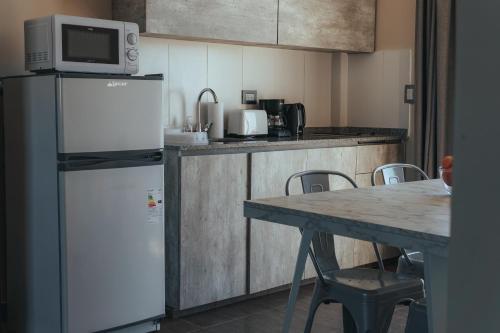 Una cocina con refrigerador y una mesa con sillas. en Solana - Apart Hotel & Club de Tenis, en Santa Clara del Mar