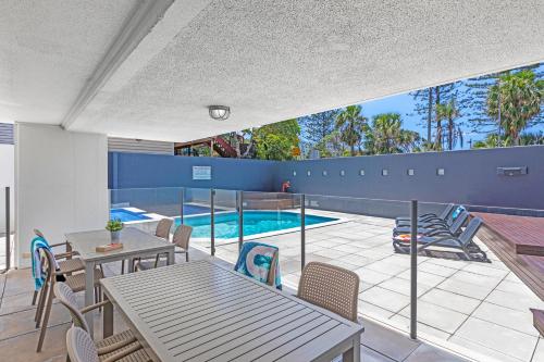 a patio with tables and chairs and a swimming pool at Northwind Beachfront Apartments in Mooloolaba