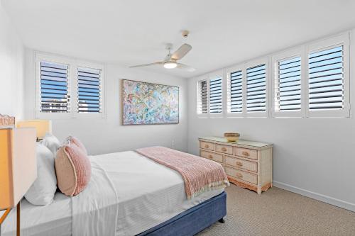 a bedroom with a bed and a dresser and windows at Northwind Beachfront Apartments in Mooloolaba