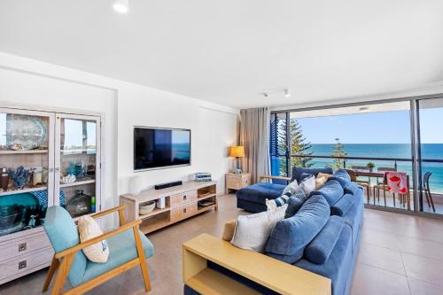 a living room with a blue couch and a television at Northwind Beachfront Apartments in Mooloolaba