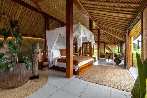 a bedroom with a canopy bed in a house at Samanvaya Luxury Resort & Spa - Adults Only in Sidemen