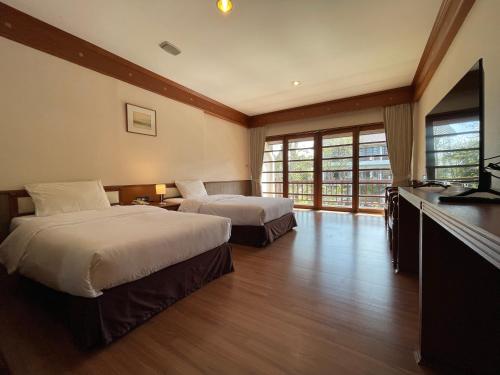 a hotel room with two beds and a television at Korat Resort Hotel in Nakhon Ratchasima